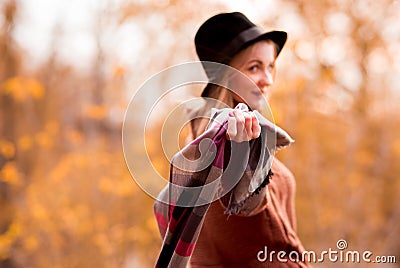 Shawl in focus, man blurred. Beautiful blond girl in a black felt hat holding a gray checkered with a red plaid. horizontal photo Stock Photo