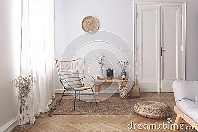 Sheer white curtains on the window of a white living room interior with a striped, linen pillow on a modern wicker chair Stock Photo