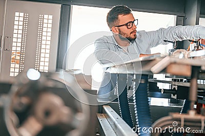 Sheet cutting machine. Operating device. Print house worker in white clothes is indoors Stock Photo