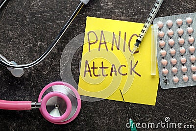 Sheet of paper with words PANIC ATTACK, stethoscope and medicines on dark table Stock Photo