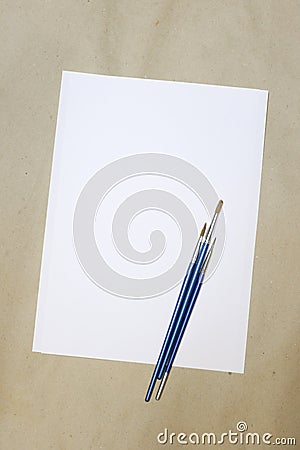 Sheet of white paper and artistic brushes on a crafting background Stock Photo