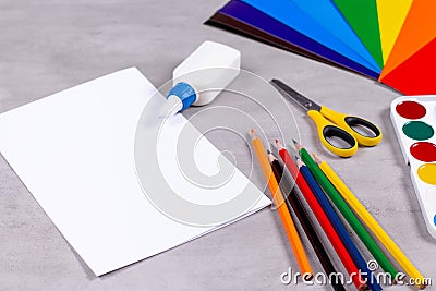 Sheets of paper, glue and scissors on a table Stock Photo