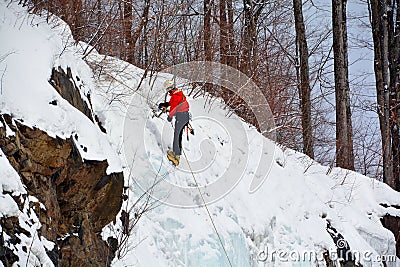 Solo ice climber swinging ice tool ascending huge ice wall Editorial Stock Photo