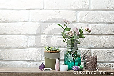 A shelf for decorative ornaments. Home-made beautiful things. Crystals, candlesticks, flowers in a jar against a white brick wall Stock Photo