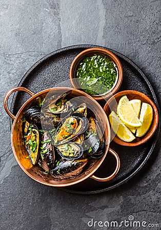 Shellfish Mussels in copper bowl, lemon, herbs sauce. Stock Photo