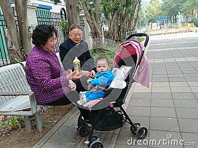 Shenzhen, China: Grandparents and grandchildren rest on the sidewalk Editorial Stock Photo