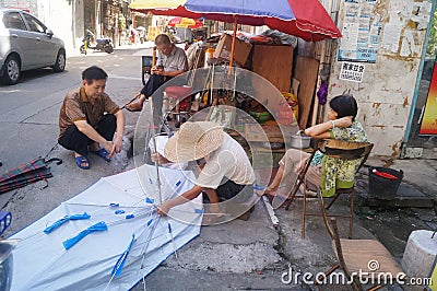 Shenzhen, China: street repair old umbrella Editorial Stock Photo