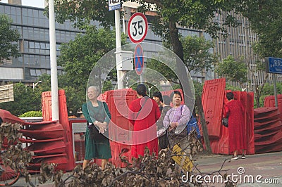 Shenzhen, China: a street view of elderly people waiting for tour buses and women on bicycles Editorial Stock Photo
