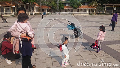 Shenzhen, China: Young mothers or grandmothers play outdoors with their children Editorial Stock Photo