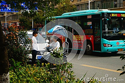 Shenzhen, China: a young woman riding an electric car chats with a man on the road Editorial Stock Photo