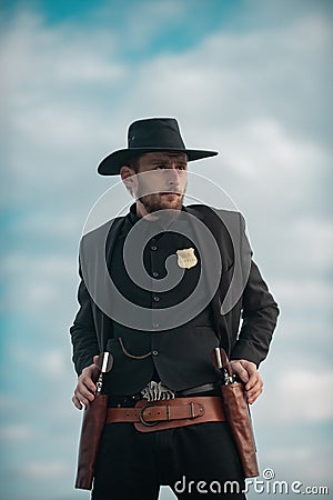 Sheriff officer in black suit and cowboy hat. Man with wild west guns, vintage pistol revolver and marshal ammunition Stock Photo