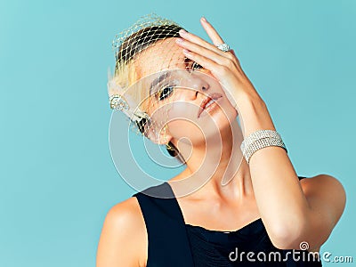 Shes all about being elegant and classy. Studio shot of an elegantly dressed young woman posing against a blue Stock Photo