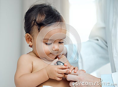 Shes so curious about every little thing. Closeup shot of a paediatrician using a stethoscope during a babys checkup in Stock Photo