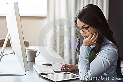 Shes a diligent worker. a young businesswoman sitting at a desk using a digital tablet. Stock Photo
