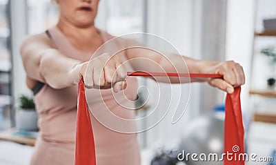 Shes getting stronger with every stretch. an unrecognizable woman exercising with a resistance band during her Stock Photo
