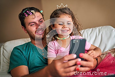 Shes given Dad a real makeover. a father and his little daughter taking a selfie together while playing dress-up at home Stock Photo