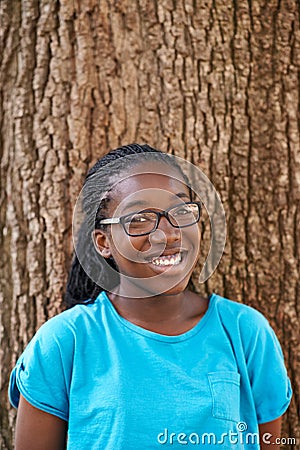 Shes not a tree hugger but she sure loves em. Portrait of a teenager smiling while standing against a tree. Stock Photo