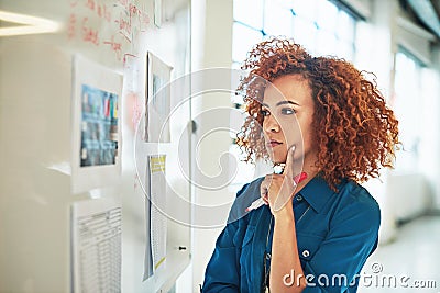 Shes a problem solver. a designer brainstorming on a whiteboard in an office. Stock Photo