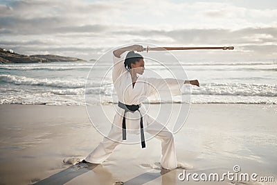 Shes a professional stick fighter. Full length shot of an attractove young female martial artist practicing karate on Stock Photo