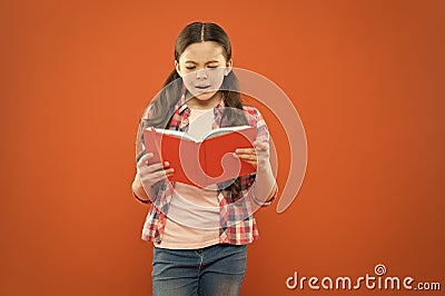 Shes a true bookworm. Adorable small child reading book on orange background. Cute little girl reading for fun Stock Photo