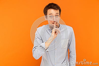 Shh, it`s secret! Businessman holding finger near mouth and look Stock Photo