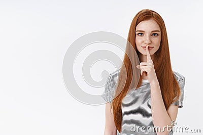 Shh secrets must save. Charming attractive self-assured redhead girl straight ginger hair show index finger lips seal Stock Photo