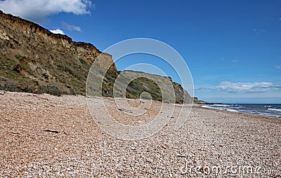 The shingle beach at Eype in Dorset on a sunny day, The sandstone cliffs of the Jurassic coast can be seen in the background Stock Photo