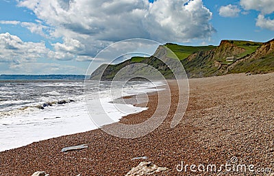 The shingle beach at Eype in Dorset on a sunny day, The sandstone cliffs of the Jurassic coast can be seen in the background Stock Photo