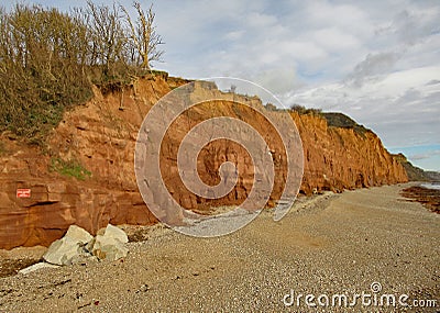 The shingle beach at Sidmouth in Devon with the red sandstone cliffs of the Jurassic coast in the background Stock Photo