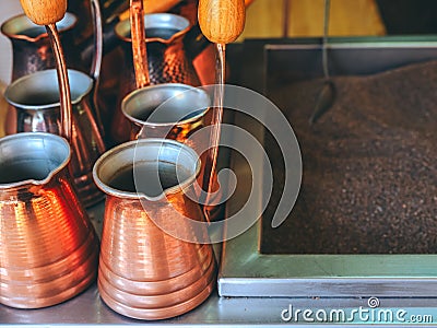 Shiny bronze-colored metal turks stand next to sand to make oriental coffee Stock Photo