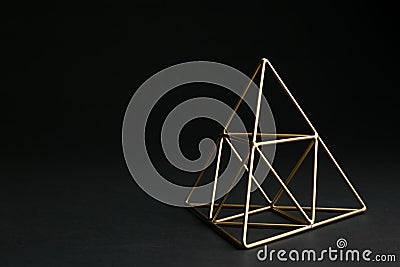 Shiny decorative gold pyramid on black background. Stock Photo