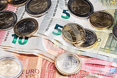 Shiny Euro coins on top of Euro banknotes, five and ten bills. Bailout money Stock Photo