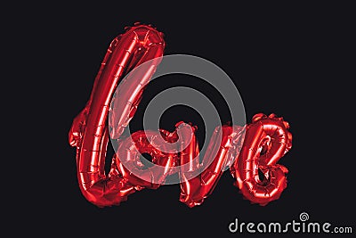 Shiny red balloon forming the word `love` on dark black background Stock Photo