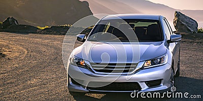 Shiny silver car parked on a sunny mountain road Stock Photo