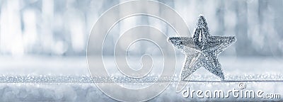 Shiny silver christmas star with defocused christmas lights in the background. Christmas banner. Stock Photo