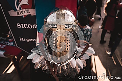 Shiny silver medieval iron knight helmet with a golden cross, full of scratches due to battles Editorial Stock Photo