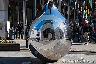 Shiny stainless steel tear drop shaped sculpture seen on a street in Manhattan New York. There is a reflection of a large building Editorial Stock Photo