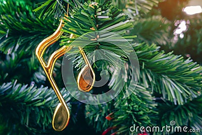 Shiny treble clef ornament or gold music notes hanging on pine tree. Stylish christmas decorations. Christmas and New Year display Stock Photo