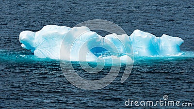 Shiny turquoise Iceberg surrounded by turquoise shiny water, Greenland Stock Photo