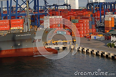 A ship being unloaded, Trucks, Containers, and Cranes Editorial Stock Photo