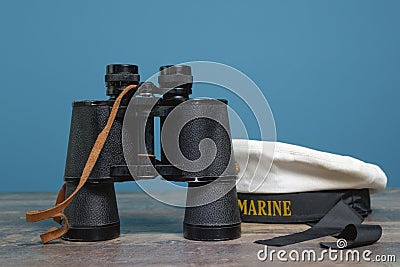Ship binoculars and peakless cap on a turquoise background on a textured wooden table Stock Photo