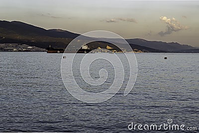 The ship enters the bay at the port at sunset against the backdrop of mountains Editorial Stock Photo