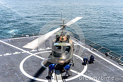 Ship`s crew release chalks and chains that ties down the Bell 212 helicopter of royal Thai navy on the flight deck of HTMS. Editorial Stock Photo