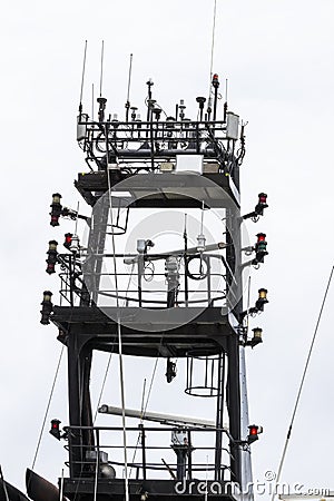 Ship`s main mast viewed from below. Restricted manoeuvrebility light illuminated. Multiple types of antennas and cables visible Stock Photo