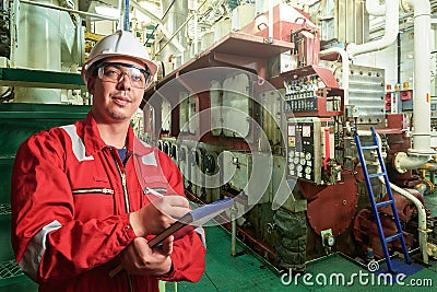 Ship`s mechanic near marine diesel generators on a merchant ship in the engine room Stock Photo