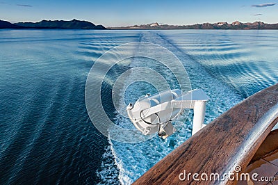 Ship`s wake and auxilliary light in the cool clear air of dawn, Alaska, USA. Stock Photo
