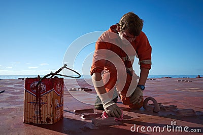 Ships crew members painting hatch cover outdoors with bright blue sky on a background. Ship maintenance concept Editorial Stock Photo