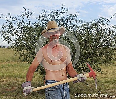 A Shirtless Cowboy Uses a Red Pickax Stock Photo