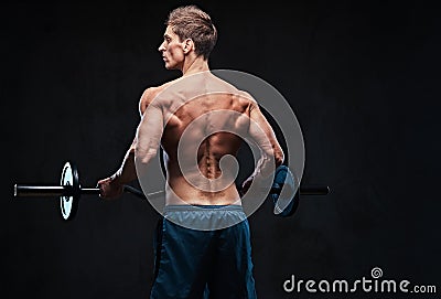 Shirtless male holds barbell over dark grey background. Stock Photo