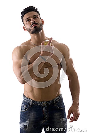 A Shirtless Man Holding a Cologne Bottle, Spraying Perfume Stock Photo